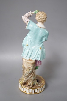 A 19th century Meissen figure of a boy holding grapes to his head, his hat full of grapes, wearing a crinoline scarf and shirt cuffs, crossed swords in blue, incise letters and numbers 17cm